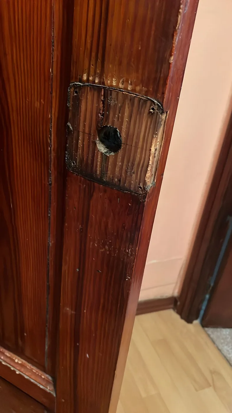 Hueco cajeado a mano en el canto de una puerta de madera antigua, preparado para alojar una cerradura nueva