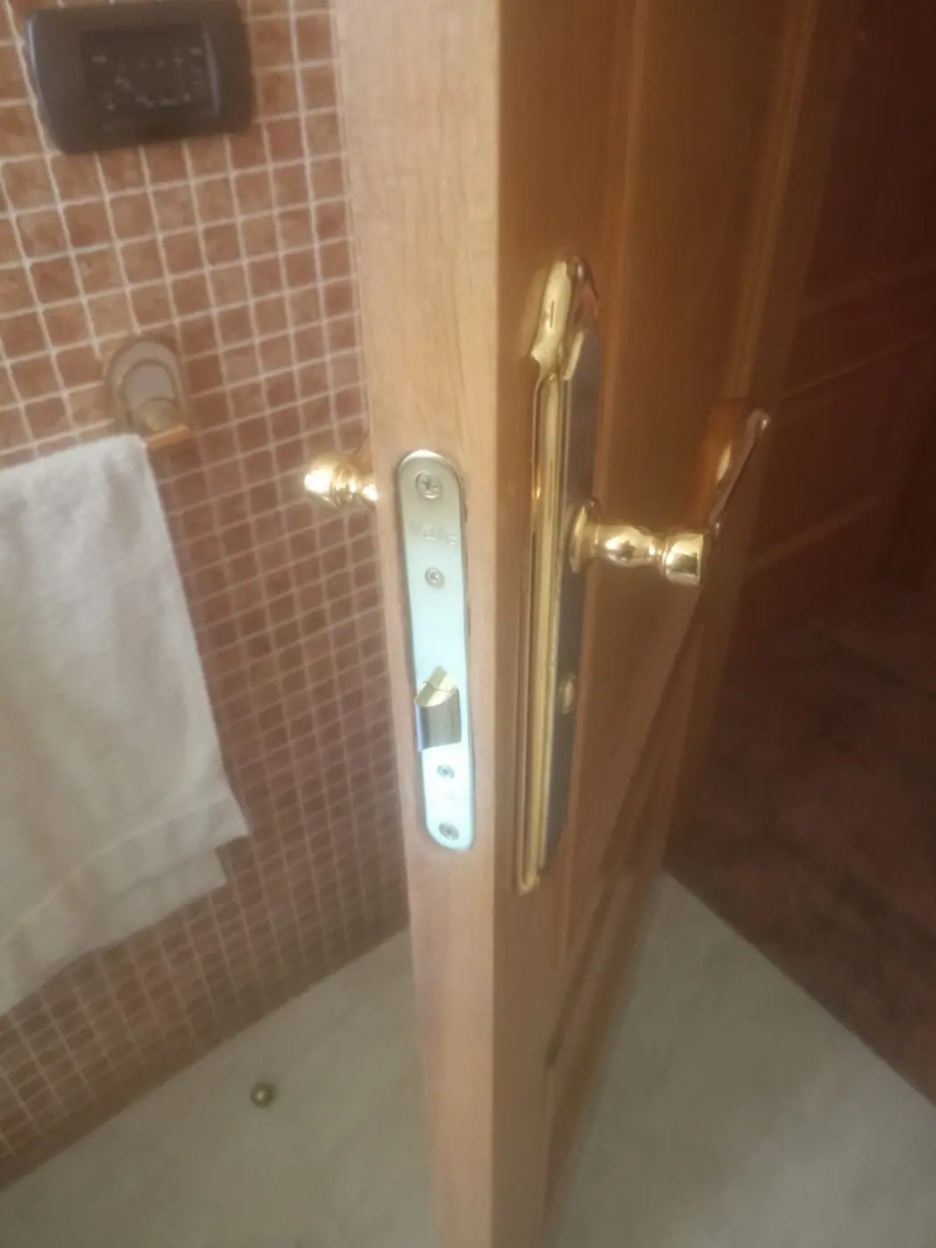 Placa y cerradura de una puerta de baño desmontadas sobre la propia hoja